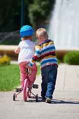 Image showing Boy and girl in park learning to ride a bike