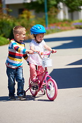 Image showing Boy and girl in park learning to ride a bike