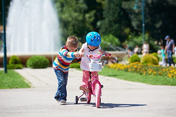 Image showing Boy and girl in park learning to ride a bike