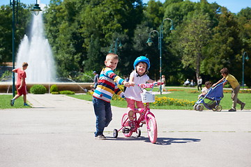 Image showing Boy and girl in park learning to ride a bike