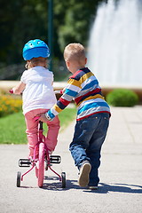 Image showing Boy and girl in park learning to ride a bike