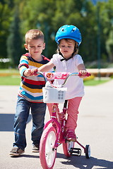 Image showing Boy and girl in park learning to ride a bike