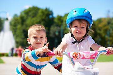 Image showing Boy and girl in park learning to ride a bike