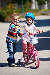 Image showing Boy and girl in park learning to ride a bike