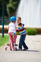 Image showing Boy and girl in park learning to ride a bike