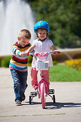 Image showing Boy and girl in park learning to ride a bike