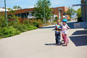 Image showing Boy and girl in park learning to ride a bike