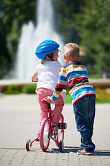 Image showing Boy and girl in park learning to ride a bike