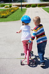 Image showing Boy and girl in park learning to ride a bike