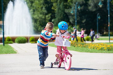 Image showing Boy and girl in park learning to ride a bike