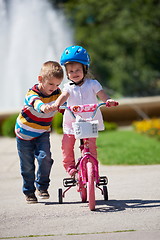 Image showing Boy and girl in park learning to ride a bike