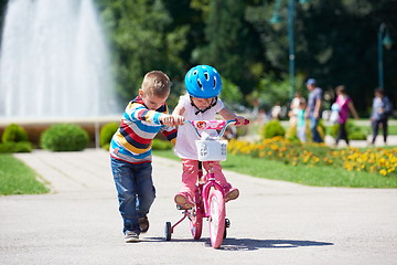 Image showing Boy and girl in park learning to ride a bike