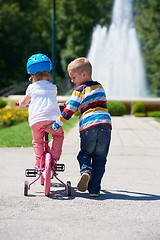 Image showing Boy and girl in park learning to ride a bike