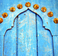 Image showing dirty stripped paint in the blue wood door and rusty nail