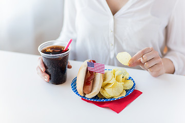 Image showing close up of woman eating chips, hot dog and cola