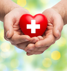 Image showing male hands holding red heart with white cross