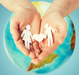 Image showing human hands holding paper couple over earth globe