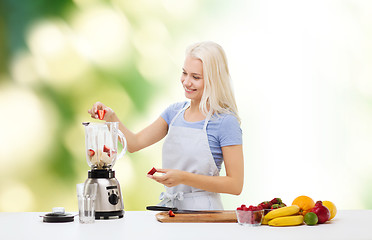 Image showing smiling woman with blender preparing shake