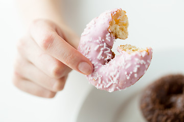 Image showing close up of hand holding bitten glazed donut