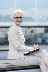 Image showing young smiling businesswoman with notepad outdoors