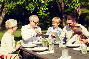 Image showing happy family with tablet pc at table in garden