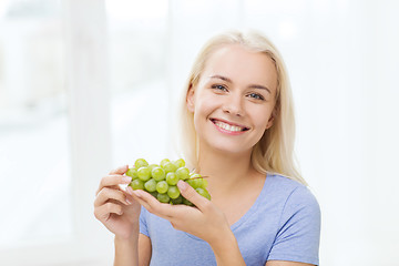 Image showing happy woman eating grapes at home