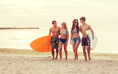 Image showing smiling friends in sunglasses with surfs on beach