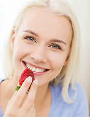 Image showing happy woman eating strawberry at home