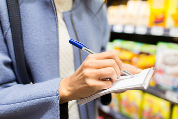 Image showing close up of woman writing to notepad in market