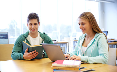 Image showing happy students with laptop and books at library