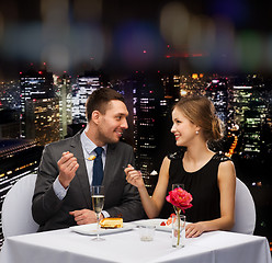 Image showing smiling couple eating dessert at restaurant