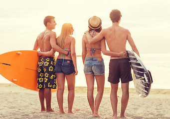 Image showing smiling friends in sunglasses with surfs on beach