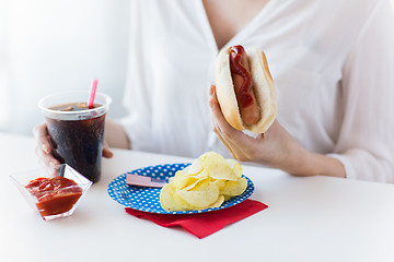 Image showing close up of woman eating hot dog with coca cola