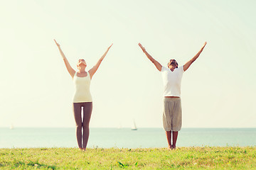 Image showing smiling couple making yoga exercises outdoors