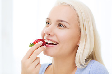 Image showing happy woman eating strawberry at home