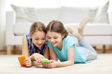 Image showing happy girls with smartphones lying on floor