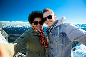 Image showing happy teenage couple taking selfie over mountains