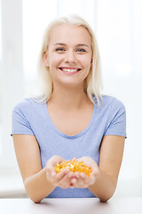 Image showing happy woman holding fish oil capsules at home