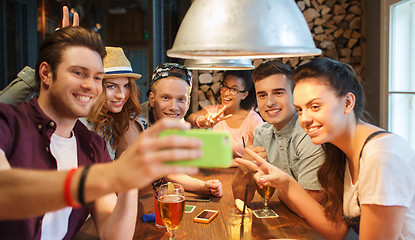 Image showing happy friends with smartphone taking selfie at bar