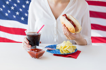 Image showing close up of woman eating hot dog with coca cola