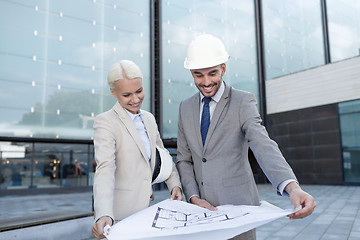 Image showing smiling businessmen with blueprint and helmets