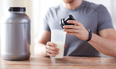 Image showing close up of man with protein shake bottle and jar