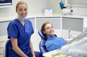 Image showing happy female dentist with patient girl at clinic