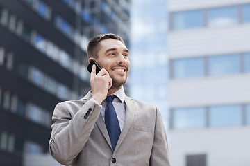 Image showing smiling businessman with smartphone outdoors