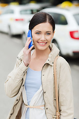 Image showing smiling woman with smartphone over taxi in city