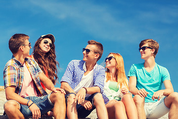 Image showing group of smiling friends sitting on city street