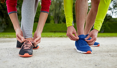 Image showing close up of couple tying shoelaces outdoors