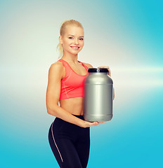 Image showing smiling sporty woman with jar of protein