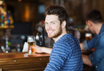 Image showing happy young man drinking beer at bar or pub