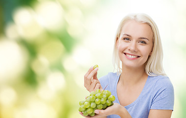 Image showing happy woman eating grapes